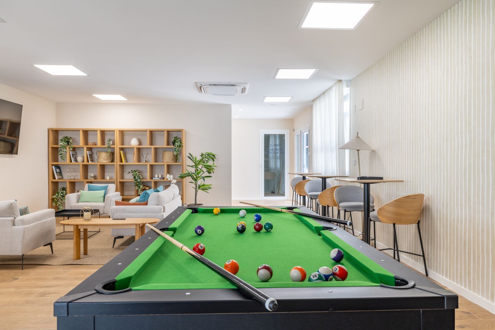 Modern office lounge with pool table, comfortable seating, and bookshelves.